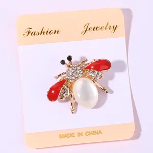 Exquisite rhinestone insect brooch featuring red enamel wings and white pearl body detail.