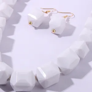 Dettaglio in primo piano della collana di perle acriliche geometriche bianche e orecchini set.