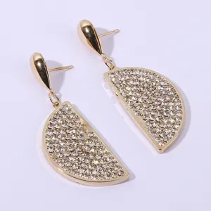 Close-up detail of sparkling rhinestone half-circle lemon pendant earrings in gold finish.