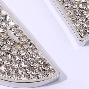 Close-up detail of silver crystal paved lemon slice pendant earrings, shiny rhinestone decor.
