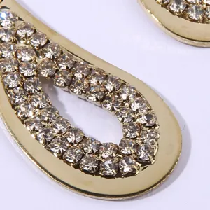 Stunning close-up detail of elegant gold teardrop rhinestone earrings sparkling brightly.