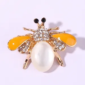 Close-up detail of rhinestone bee brooch, golden alloy finish with yellow enamel wings and opal.