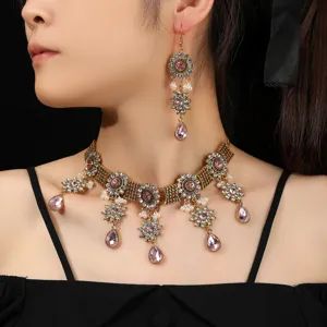 Close-up detail of vintage crystal choker necklace and drop earrings set with pink stones.