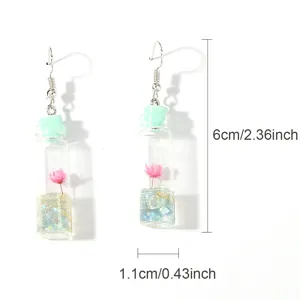 Mini glass drift bottle pendant earrings featuring pink dried flower close-up view.