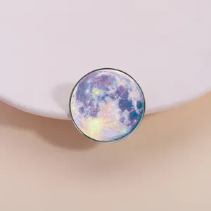 Close-up of a round metal brooch featuring a vibrant starry galaxy moon design, detailed accessory.