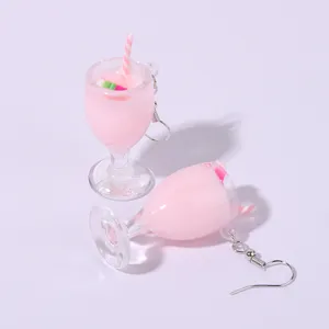 Detail shot of cute pink juice cup resin earrings with miniature straw and fruit slices.