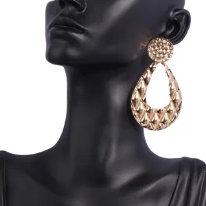 Détail de boucles d'oreilles pendantes dorées texturées, bijoux en métal mode pour femmes.