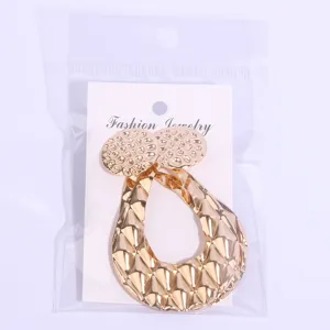 Gros plan élégant de boucles d'oreilles géométriques en métal doré texturé sur support.
