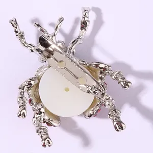 Detailed view of the silver beetle brooch back, showing pin and white base structure.