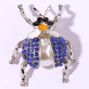 Vintage beetle brooch featuring vibrant blue rhinestones and a large pearl body in silver tone.