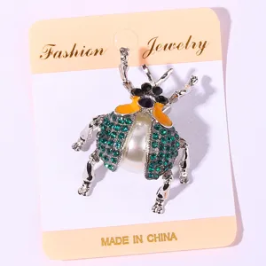 Detailed view of the vintage beetle brooch featuring sparkling green rhinestones and pearl body.