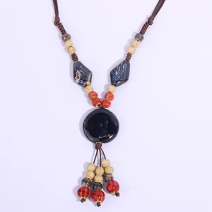 Detailed view of handmade ceramic pendant necklace featuring vintage ethnic braided rope and beads.