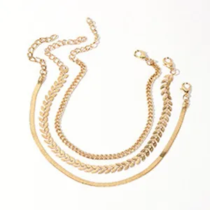 Detailweergave van een gouden enkelbandjesset met diverse fijne schakels voor op het strand.