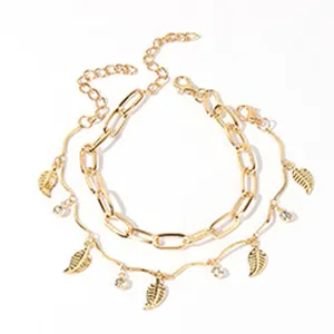 Dubbellaagse gouden enkelband met bladhangers en strass-steentjes, perfecte zomerstrandstijl.