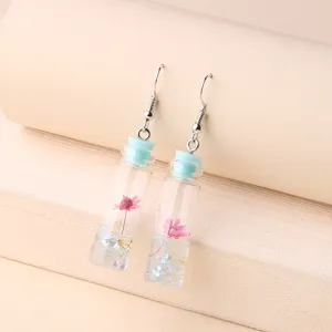 Detailed view of cute glass drift bottle earrings with pink dried flowers and sparkle.