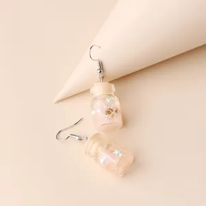 Close-up detail of summer beach wishing bottle earrings with mini shells and glittering stars.