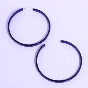 Close-up detail of oversized blue acrylic hoop earrings, showing smooth glossy finish.
