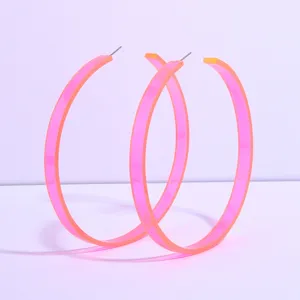Close-up of oversized neon pink acrylic hoop earrings, minimalist transparent resin design details.