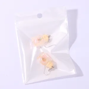 Detail shot of summer ocean wishing bottle pendant earrings in clear storage bag.