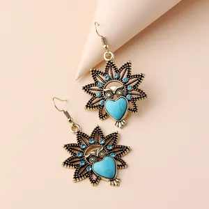 Close up view of vintage owl dangle earrings featuring turquoise heart stone and blue rhinestones.