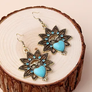 Detailed close-up of vintage owl drop earrings with turquoise heart stones and crystal details.