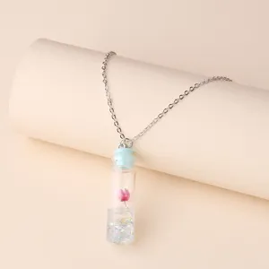 Charming drift bottle necklace detail, featuring a cute glass vial with dried flower and sparkle.