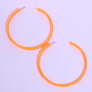 Neon orange acrylic hoop earrings detail, statement oversized circle jewelry accessory.