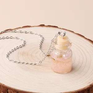 Detailed view of a charming glass wish bottle pendant necklace with sparkly pink sand inside.