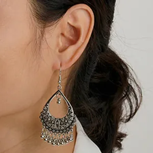 Detail shot of vintage silver teardrop dangle earrings with intricate cutout patterns and beads.
