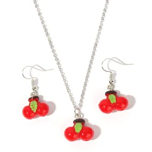 Close-up detail of a cute cherry necklace and earrings jewelry set with red fruit pendants.