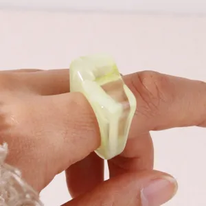 Detailed close-up shot of a chic geometric acrylic resin ring worn on a finger elegantly.