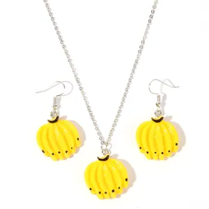 Close-up of yellow banana pendant and earrings detail, cute fruit jewelry set parts.