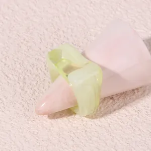 Detailed close-up view of a trendy geometric light green acrylic ring on a stylish pink ring holder.