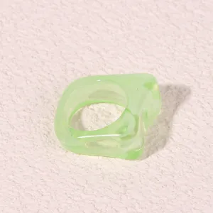Close-up detail shot of a chunky light green geometric acrylic ring, modern minimalist style.