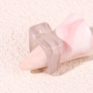 Detail shot of a chunky translucent grey acrylic geometric ring displayed on a pink cone prop.