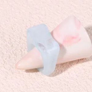 Close-up detail of light blue geometric acrylic resin ring displayed on a soft pink cone stand.