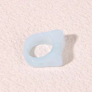 Detailed close-up of a light blue geometric resin acrylic ring, modern minimalist style.