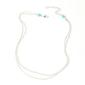 Gedetailleerd overzicht van een meerlaagse zilveren metalen lichaamketting met blauwe kralen.