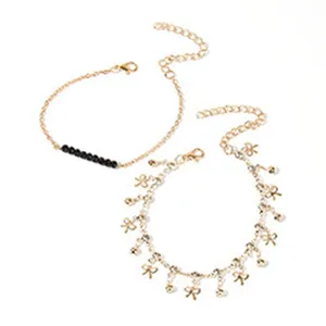 Gouden metalen ketting enkelbandje detail met zwarte kralen en schattige strikjes hangers.