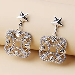 Close-up of silver rhinestone star and geometric dangle earrings, shining crystal details.