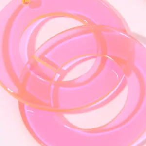 Detail shot of fluorescent pink acrylic geometric round earrings, stylish summer jewelry.