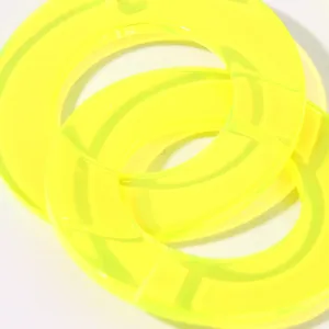 Close up of neon yellow acrylic geometric round earrings detail view, modern design style.