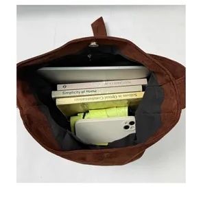 Interieurdetail van bruine suède totebag met grote capaciteit voor laptop en boeken.