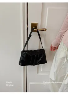 Minimalist black faux leather shoulder bag for women, chic pleated cloud design daily style.
