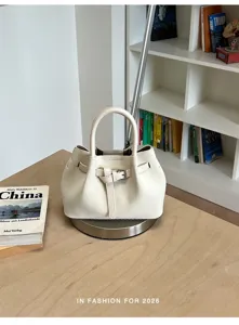 Vista detallada del elegante bolso tipo saco blanco con textura tejida exquisita y correa fina.