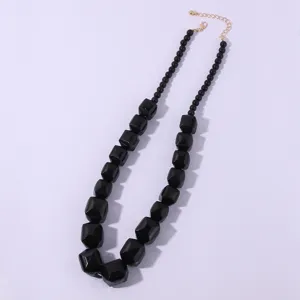 Collana di perle acriliche geometriche nere con dettagli di catena dorata elegante.