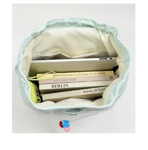 Mint green denim backpack interior detail showing large capacity, laptop and books.