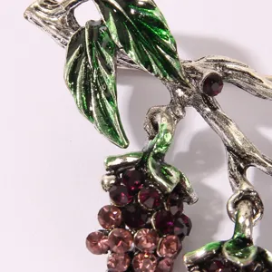 Vintage metal grape brooch detail shot, green enamel leaves with sparkling purple rhinestones.