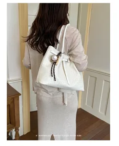 Detail view of the white woven shoulder tote bag worn by model, spacious daily commute style.