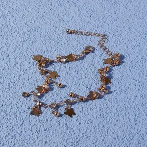 Detail shot of a rose gold butterfly charm anklet with sparkly rhinestones on textured blue background